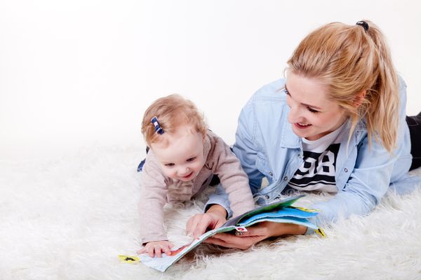 Zdjęcie uśmiechniętej kobiety z dzieckiem oglądających książkę
